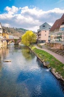 River with stone bridge and modern buildings along the shore, Calw, Black Forest, Germany