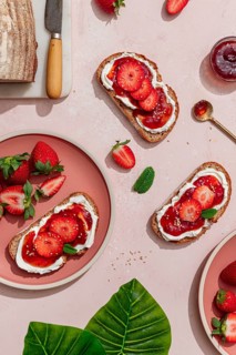 Top view of a delicious summer breakfast featuring toasted bread with cream cheese, strawberry