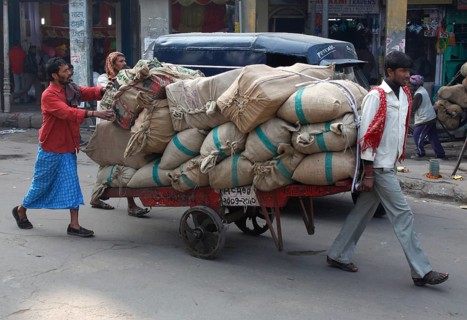 New Delhi, India, 14.01.10, Two men push a trailer loaded with bags