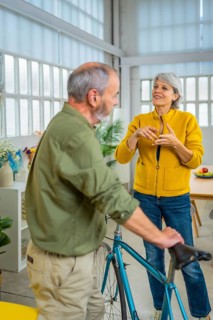 Vertical photo of a man holding a bike inside the house talking with his wife