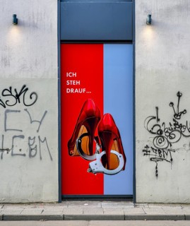 Red high heels with handcuffs, advertisement on a house wall in Grosse Präsidentenstraße, Berlin,
