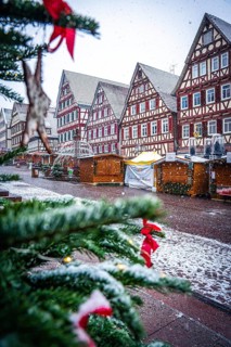 Christmas tree with decorations in front of a snow-covered half-timbered house at a market, Black