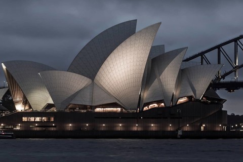 A stunning view of the Sydney Opera House illuminated against the night sky. The architectural