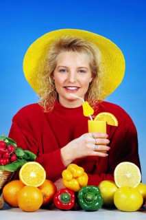 Young blonde woman drinking a glass of orange juice for breakfast, studio
