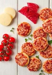 Mini pizzas, salami with mozzarella cheese, on a white table, top view, no people