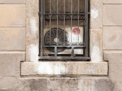 Air conditioning behind a window grille in the Barceloneta neighbourhood in Barcelona, Spain