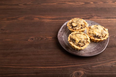 Tartlets with meat and cheese on brown wooden background. side view, copy space