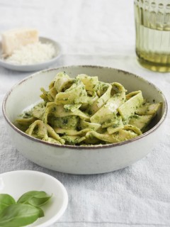 Close-up of green pasta dish, Tagliatelle with pesto with basil leaves and parmesan cheese.
