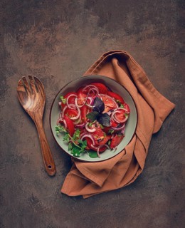 Fresh tomato salad, with red onion, spices and herbs, top view, close-up, homemade