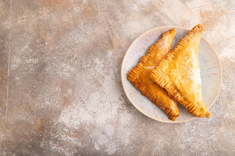 Triangles Pie, Puff Pastry, Samsa with cherry jam on brown concrete background, top view, flat lay,
