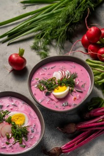 Delicious cold beetroot soup garnished with sliced radishes, hard-boiled eggs, and fresh dill.