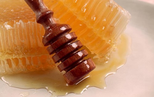 Honeycomb, with a wooden spoon-spindle, on a plate, no people