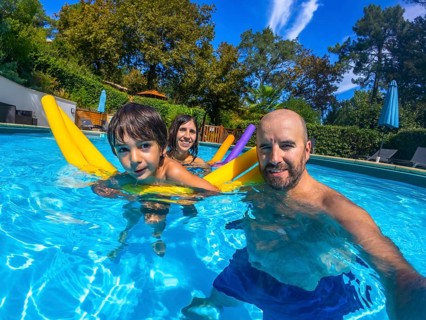 Family of three, including a father, mother, and child, smiling at the camera while swimming in a