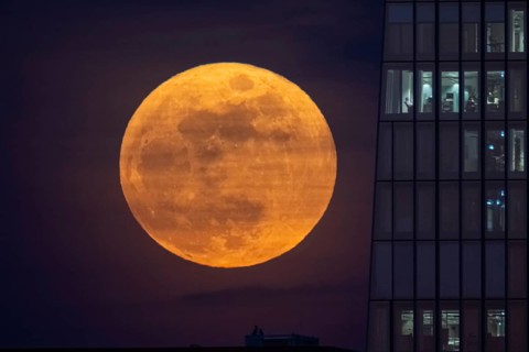 The full moon rises to the left of the European Central Bank (ECB) in Frankfurt am Main. The full