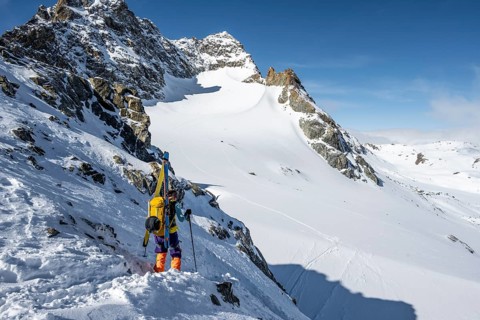 Mountaineer with skis at the fork Porta d'Es-cha, view of mountain peak Piz Kesch and glacier