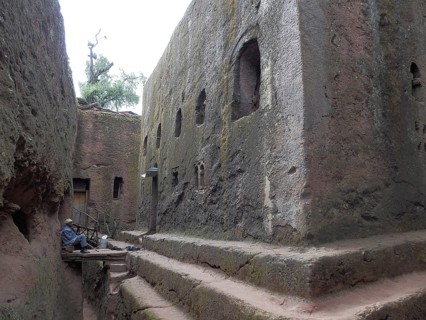 A man in traditional clothing sits on stone steps, UNESCO World Heritage Site, Lalibela Rock