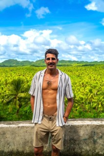 Young man posing in front of a vast coconut plantation in siargao island, philippines, enjoying the