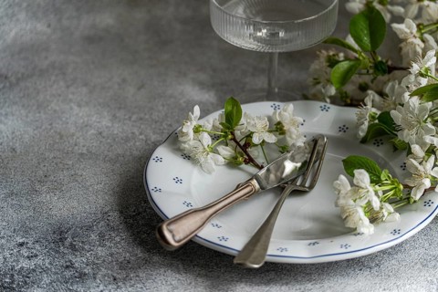 Elegant table setting featuring a white plate with delicate floral patterns, adorned with