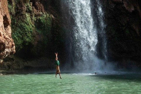 OUZOUD, MOROCCO - OCTOBER 5, 2024: A Moroccan young man jumps headfirst from the high rock into the