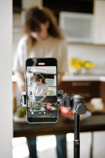 Smartphone recording a focused woman preparing healthy food in a modern kitchen