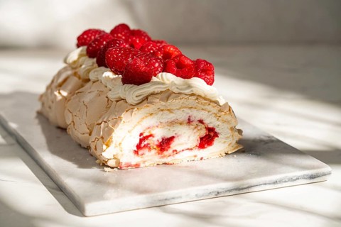 A delicious raspberry meringue roulade filled with rich cream and topped with fresh raspberries.
