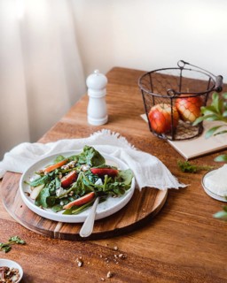 A nutritious dish of fresh spinach salad topped with crunchy apple slices, pecan nuts, and a hint