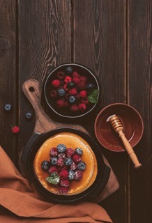Breakfast, pancakes with berries and honey, top view, homemade, no people, on a wooden background