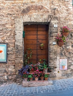 Ancient house front with door and flowerpots, Spello, Umbria, Italy