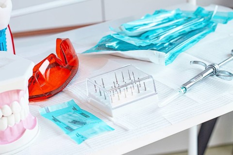 Various instruments, dental models, and hygiene items are laid out on the table in the dental