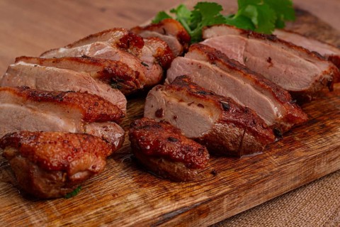 Roast duck breast, sliced, on a wooden chopping board, close-up, no people