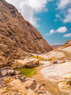 A lone adventurer stands amidst a rugged canyon, surrounded by imposing rock formations and vibrant