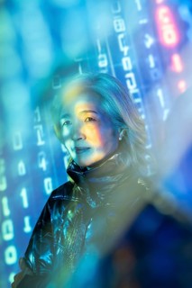 An elderly Asian woman experiences the intersection of reality and virtual worlds in the metaverse.