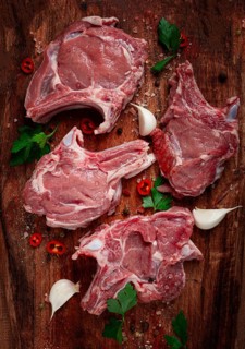 Raw calf meat, meat on the bone, meat for barbecue, cutting board, with spices and herbs, top view