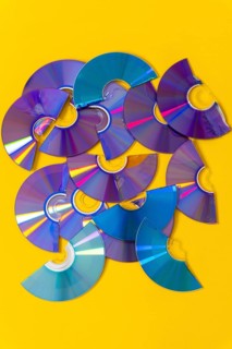 Top view of cut CDs and DVDs against a yellow background
