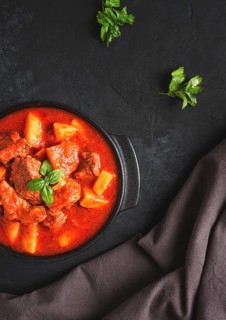 Stew with potatoes, in tomato sauce, with spices and herbs, close-up, no people, on a black