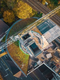 Bird's eye view of a construction site with crane and adjacent railway line, ZOB Calw