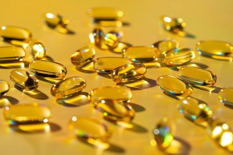 Softgel capsules filled with vitamins positioned on a vibrant yellow surface, symbolizing health