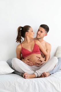 A joyful couple embracing as they cherish their pregnancy journey The expectant mother is in a red