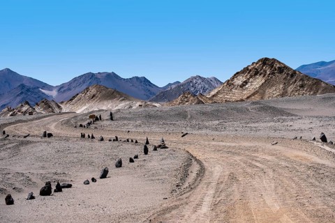 A desolate road snakes through the rocky, arid terrain of La Puna, Argentina, surrounded by rugged