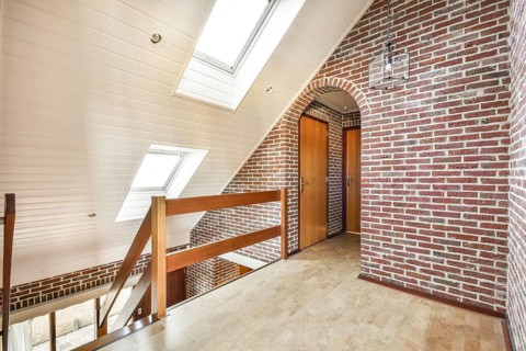 A contemporary interior design showcasing exposed brick walls, wooden railings, and natural light