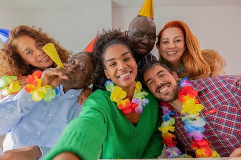 A joyful group of friends celebrates a birthday with colorful decorations, wearing party hats and