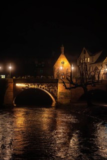 Close-up of an illuminated stone bridge at night, with clear reflection in the water, Christmas