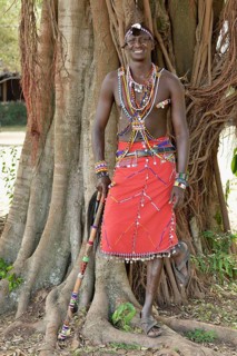 Maasai warrior wearing traditional dress and standing in a typical pose on one leg, near Enkutoto,