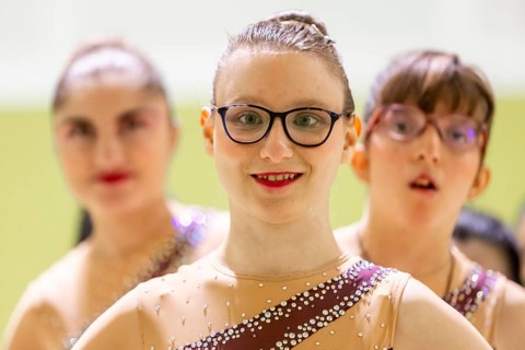 A group of diverse young gymnastic in sparkling costumes, ready for a performance. They exude