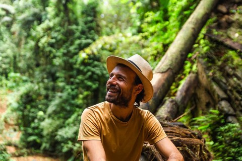 A cheerful spanish man, wearing a hat, is pictured enjoying a moment amidst the verdant rainforest