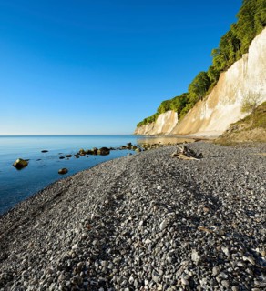 Pebble beach on the shore of the Baltic Sea in front of the chalk cliffs of the steep coast,