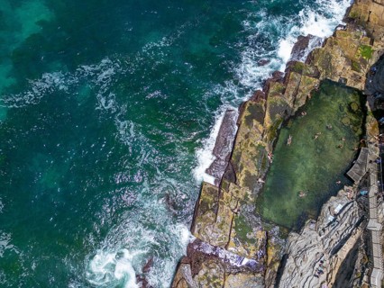 Aerial view of a striking ocean pool nestled among rugged rocks in New South Wales, Australia.