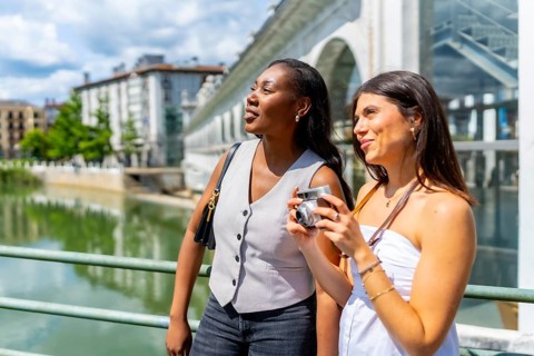 Two women enjoying sightseeing in turin, taking photos with a vintage camera near valentino park,