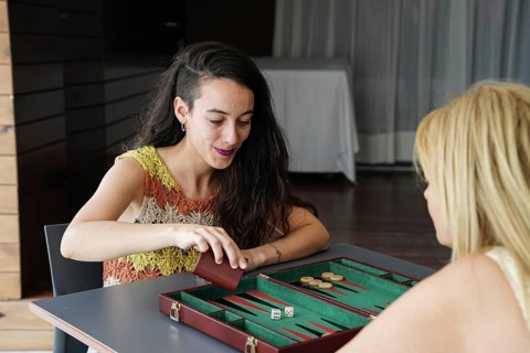 Mother and daughter engaged in a lively game of backgammon at a table, showcasing a moment of