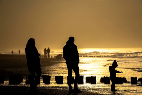 Winter on the North Sea, sunset at sea, beach walkers, coastal protection, through wooden posts,